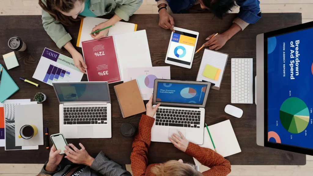 Team of people analyzing local business marketing facts and figures on table discussing digital marketing strategy and business growth insights
